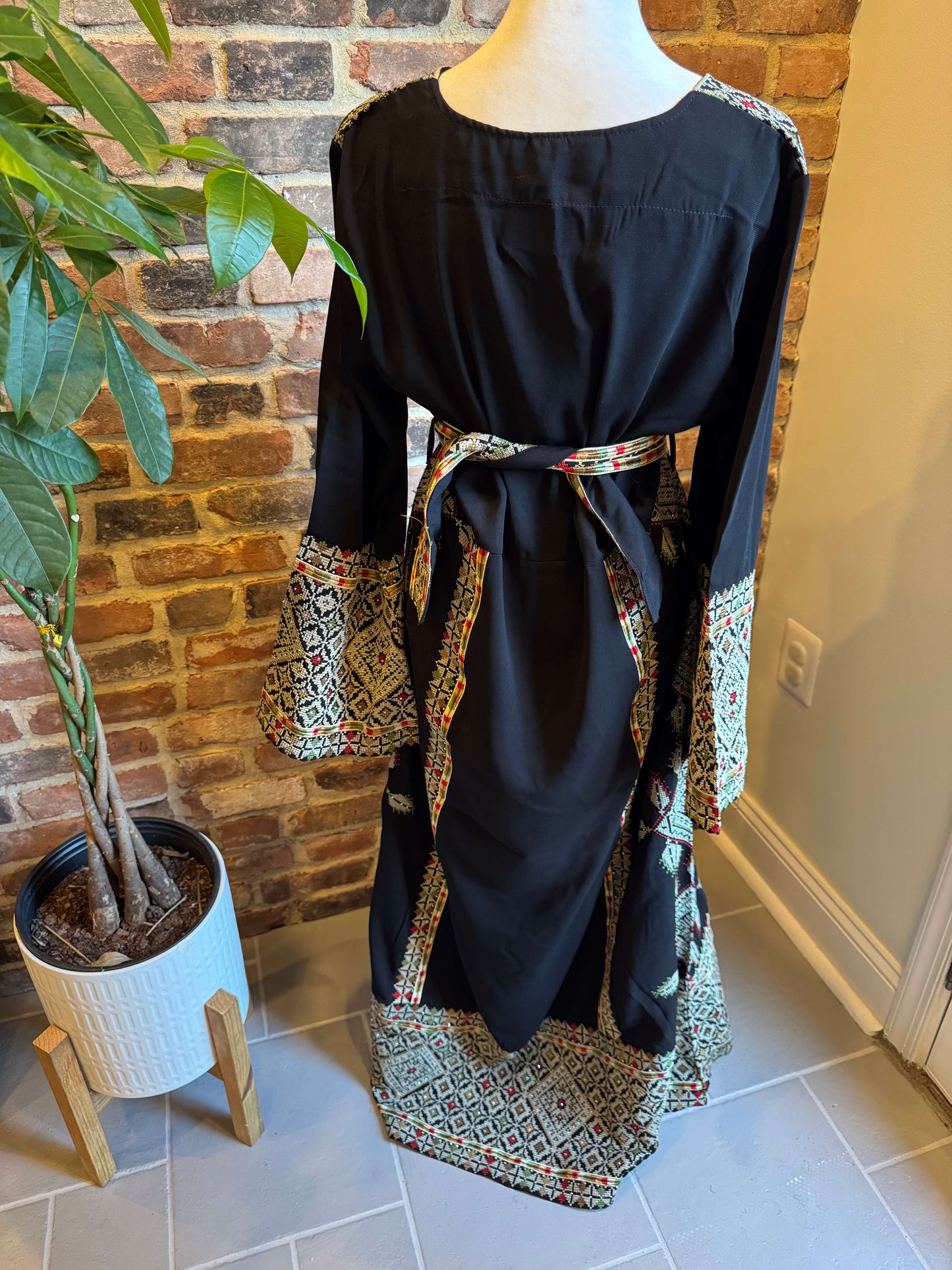 Front view of black Palestinian Ma’inat dress with green/tan embroidery back view