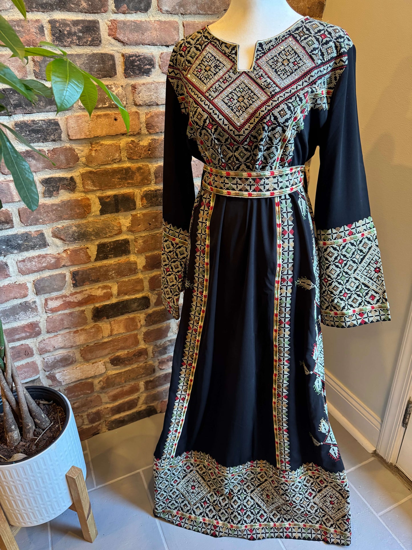Front view of black Palestinian Ma’inat dress with green/tan embroidery
