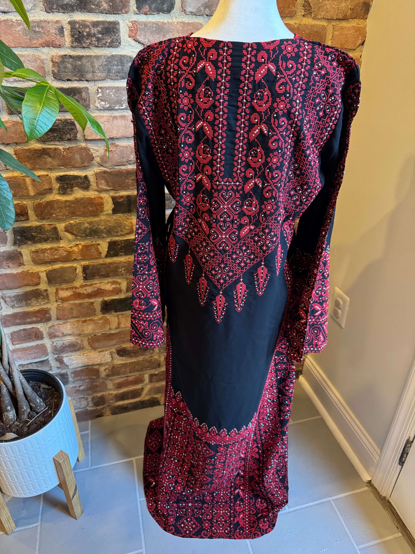 Back view of black Palestinian dress with red tatreez embroidery
