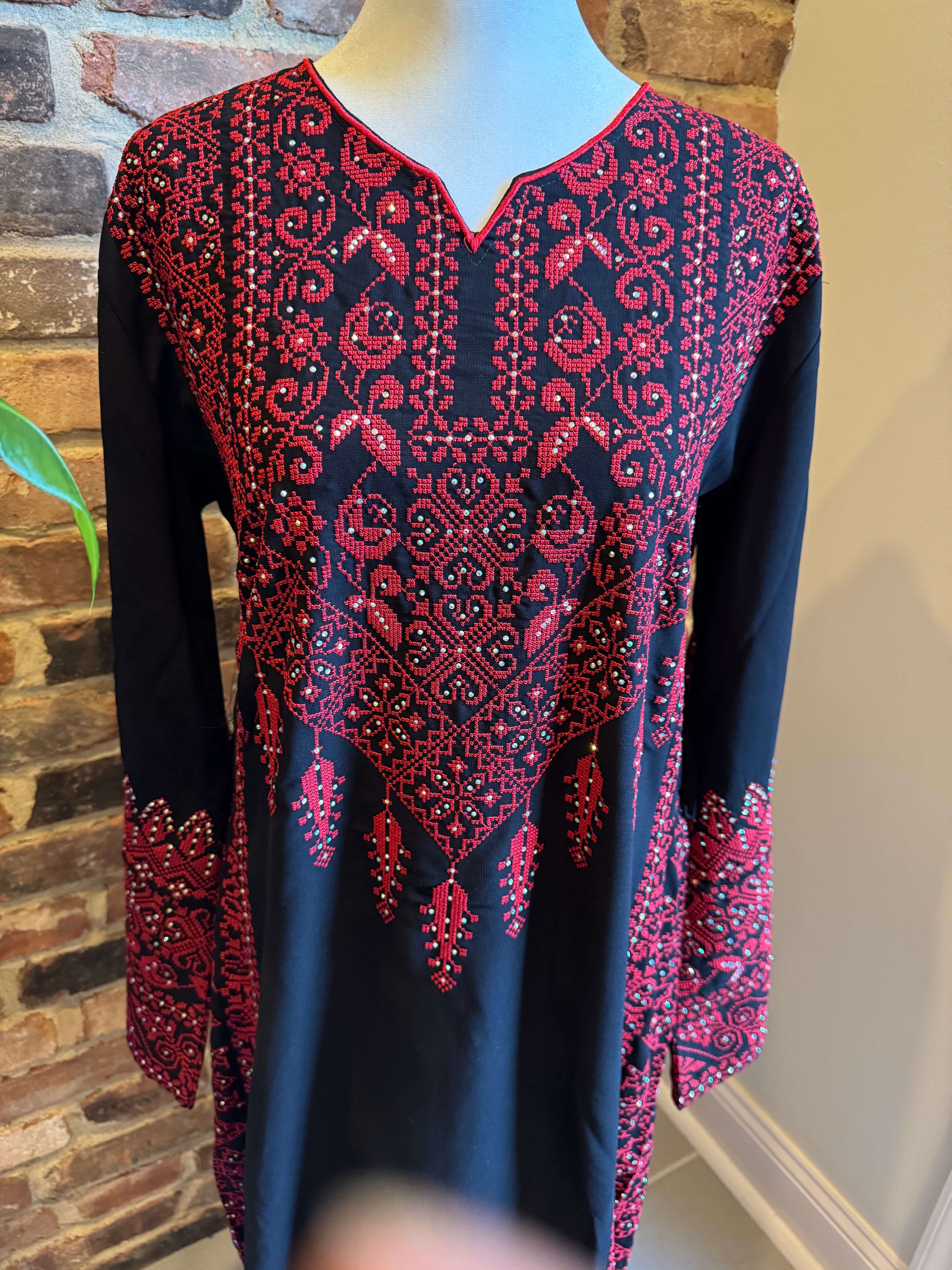 Close up view of black Palestinian dress with red tatreez embroidery