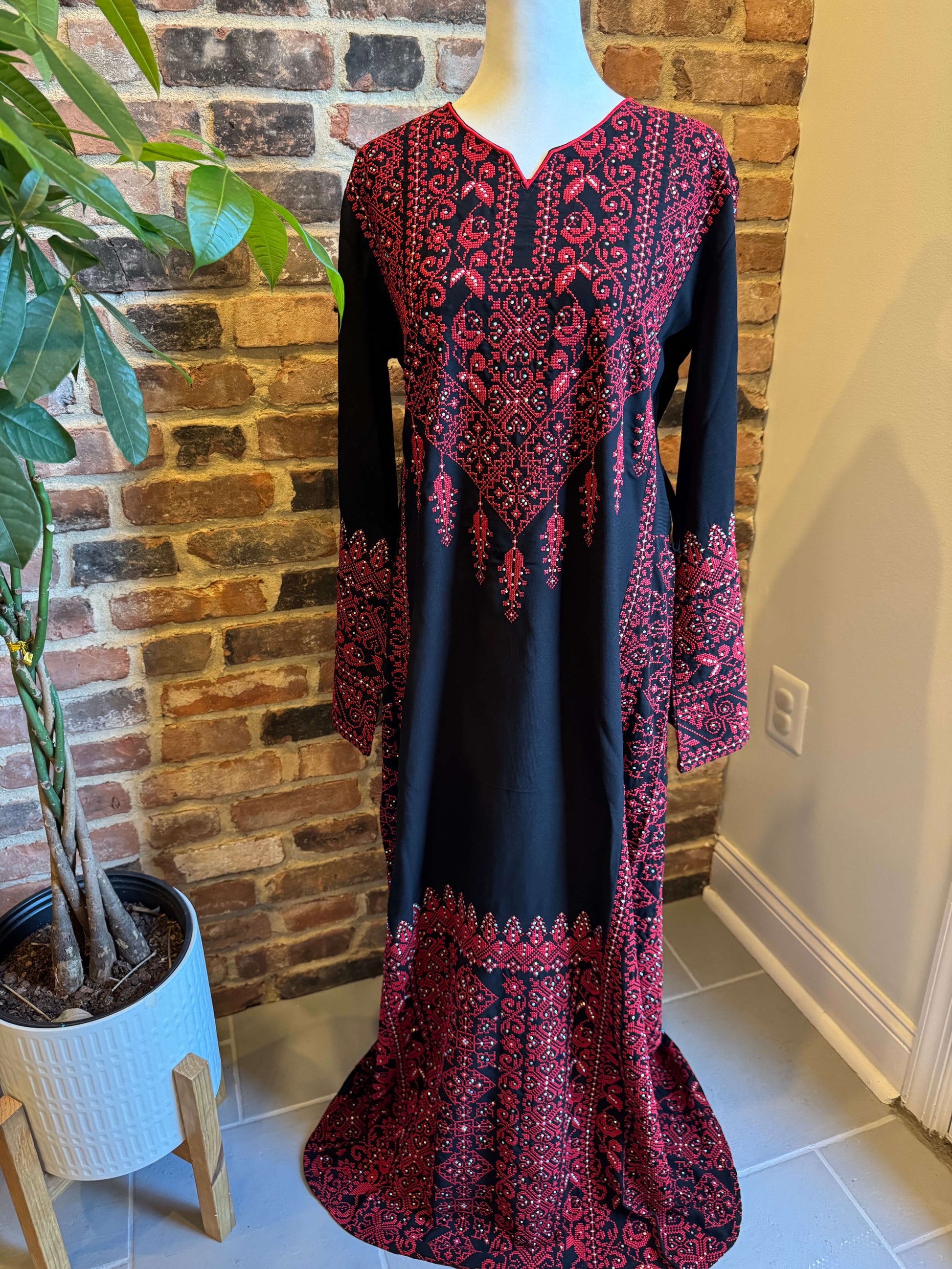 Side view of black Palestinian dress with red tatreez embroidery