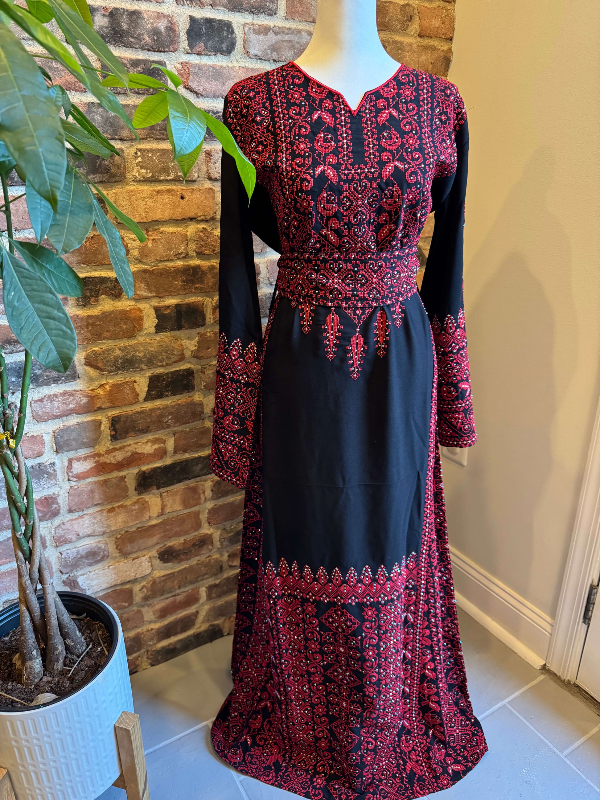 Front view of black Palestinian dress with red tatreez embroidery