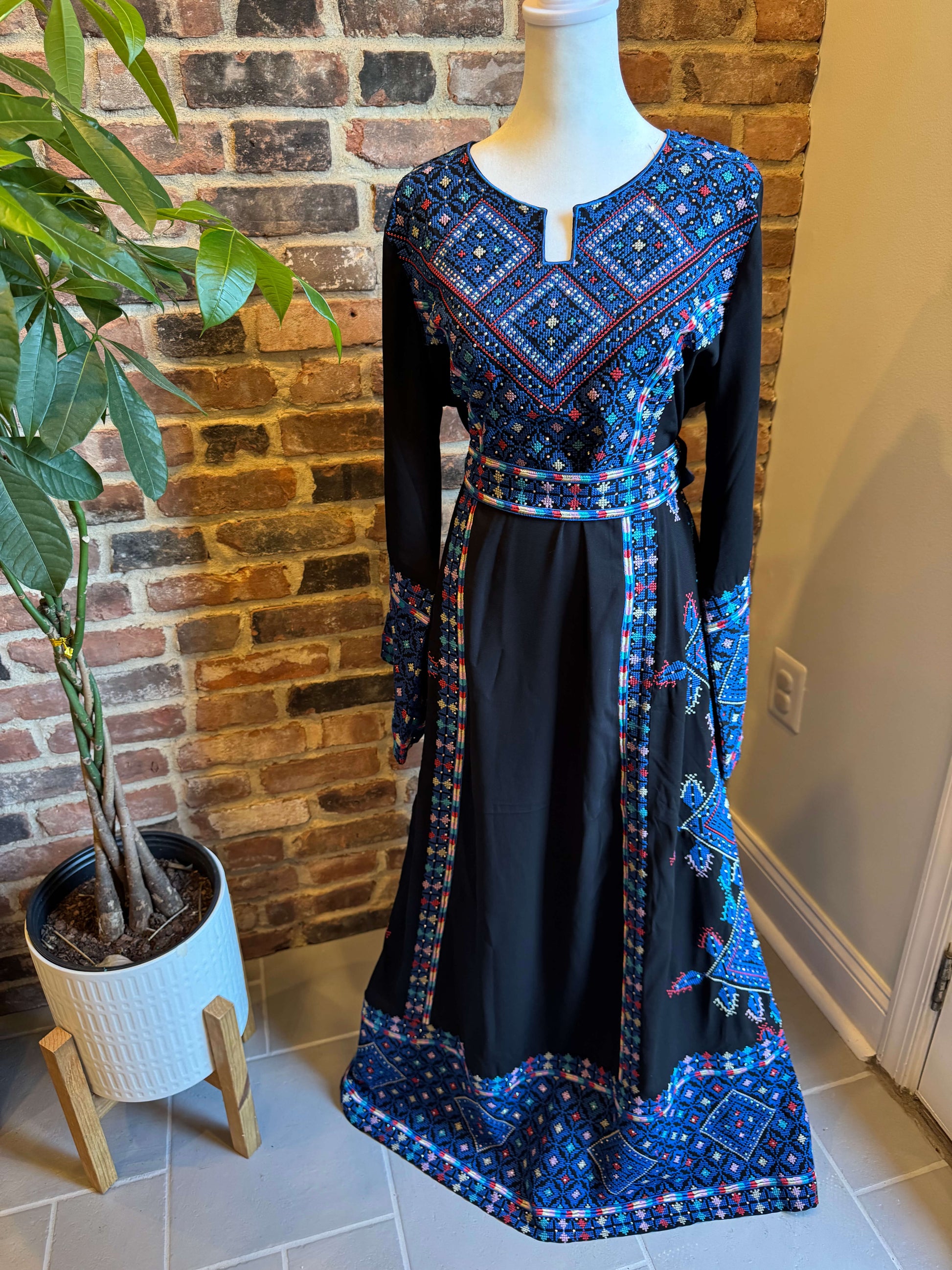 Front view of black Palestinian Ma’inat dress with blue embroidery