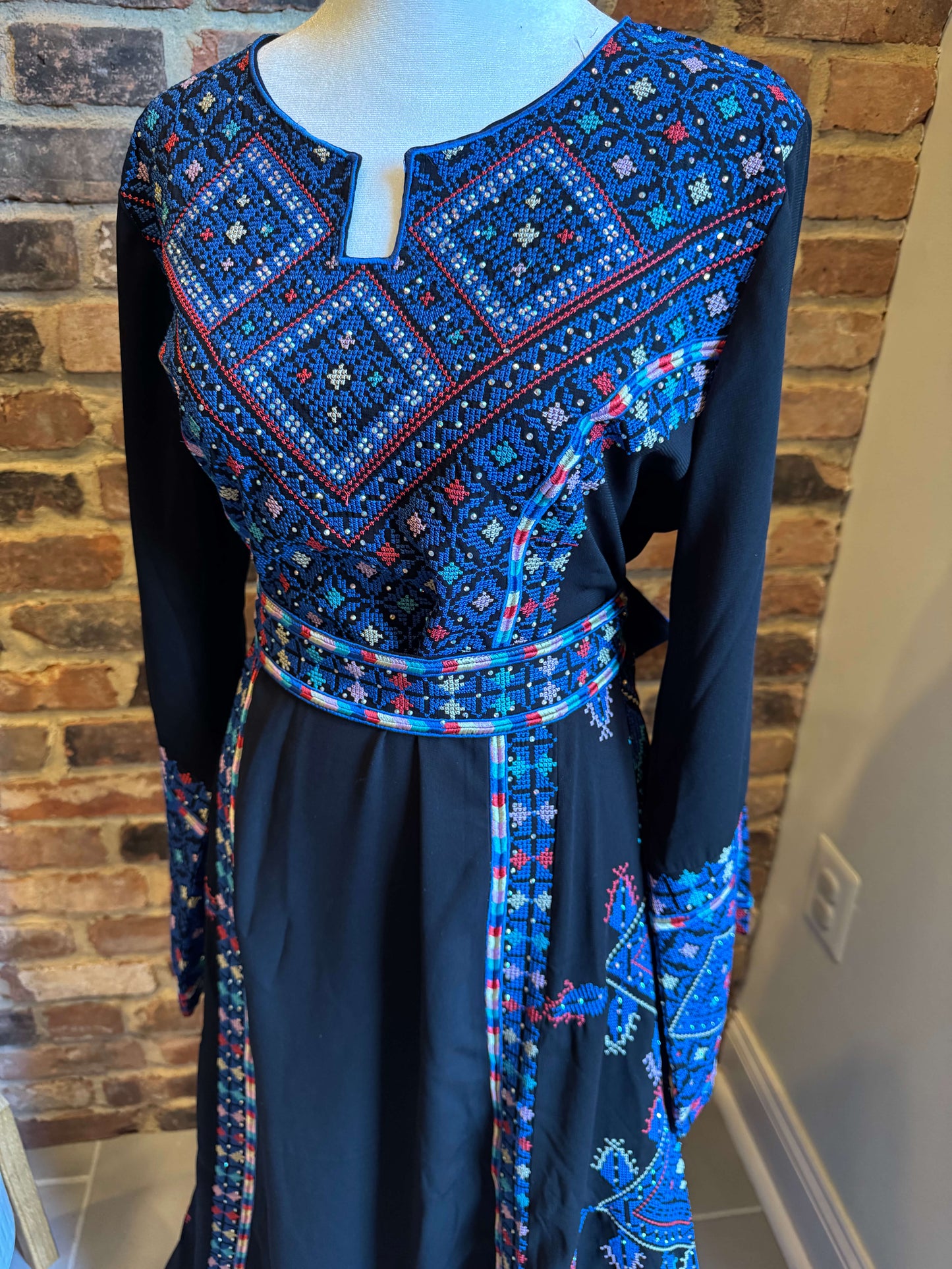 Front view of black Palestinian Ma’inat dress with blue embroidery side view